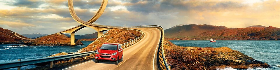 Coche rojo circulando por la carretera junto al río