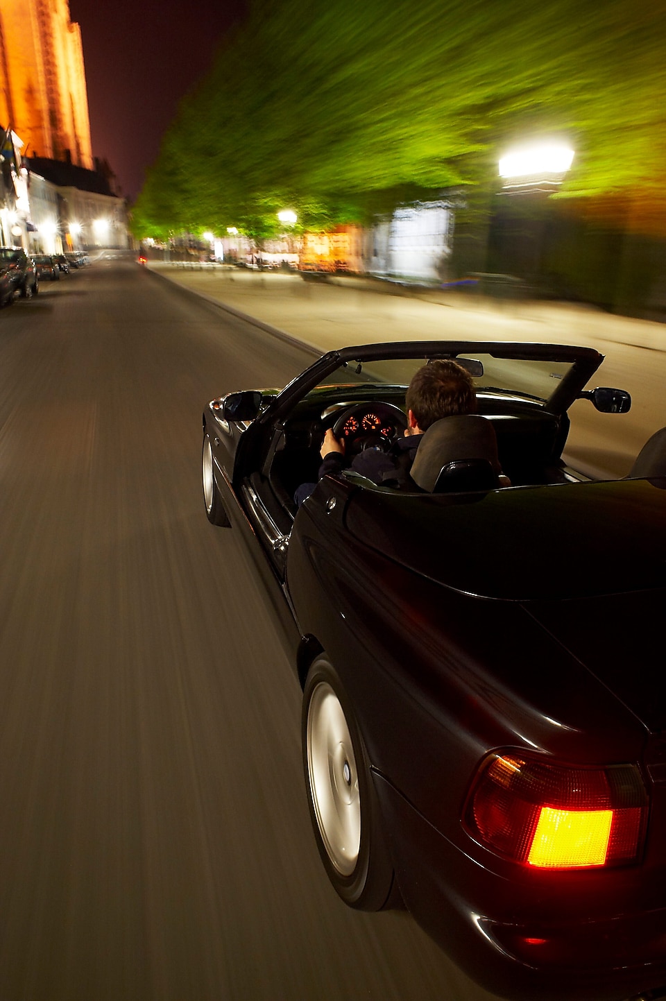 Coche negro descapotable circulando por las calles de Brujas de noche