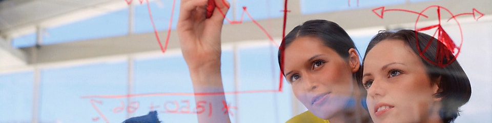 Mujer de negocios dibujando gráficos en una pizarra transparente